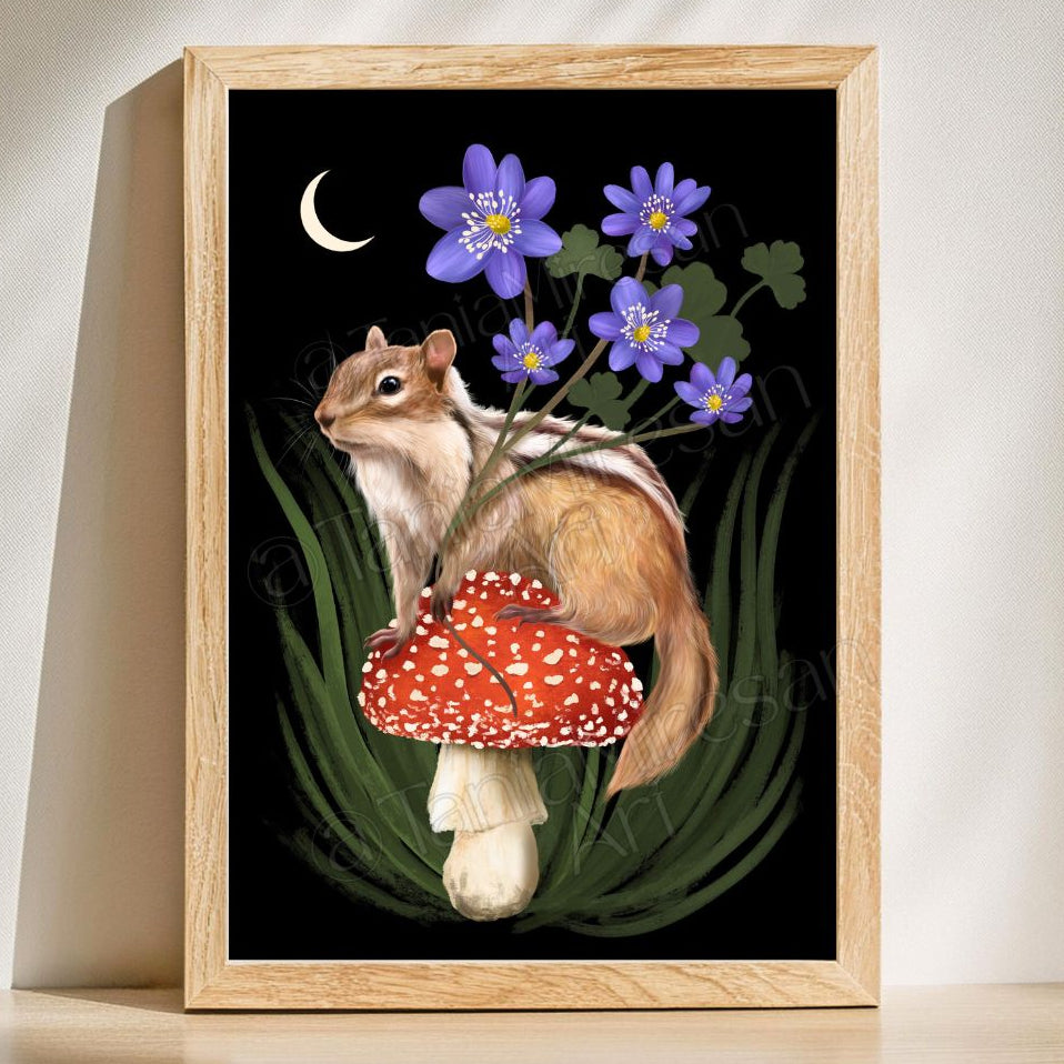 A framed art print featuring a whimsical illustration of a chipmunk sitting on a red-and-white mushroom under purple flowers and a crescent moon on a black background, displayed against a warm beige wall.