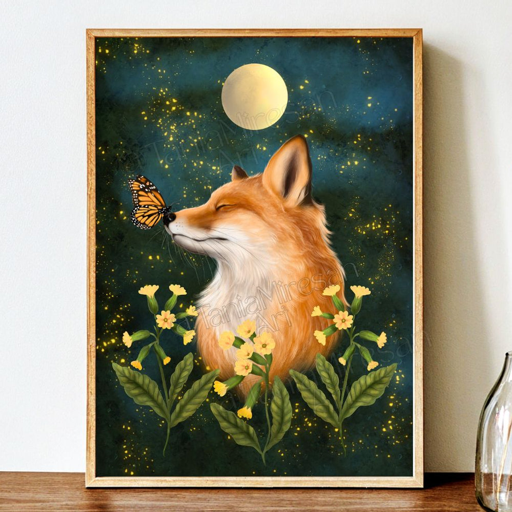 A framed art print featuring a fox surrounded by yellow flowers and a butterfly under a full moon, leaning against a white wall on a wooden surface.